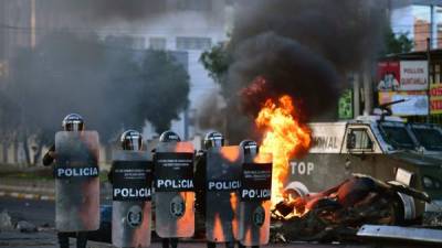 TOPSHOT - CORRECTION - Bolivian riot police stand guard during a demonstration in Cochabamba, on November 18, 2019. - Bolivia's influential Catholic Church called on Monday for a 'national dialogue' to end more than a month of violent protests in which 23 people have died, as interim president Jeanine Anez promised elections 'very soon.' (Photo by RONALDO SCHEMIDT / AFP) / The erroneous mention[s] appearing in the metadata of this photo by RONALDO SCHEMIDT has been modified in AFP systems in the following manner: [a demonstration in Cochabamba] instead of [a peaceful demonstration in La Paz]. Please immediately remove the erroneous mention[s] from all your online services and delete it (them) from your servers. If you have been authorized by AFP to distribute it (them) to third parties, please ensure that the same actions are carried out by them. Failure to promptly comply with these instructions will entail liability on your part for any continued or post notification usage. Therefore we thank you very much for all your attention and prompt action. We are sorry for the inconvenience this notification may cause and remain at your disposal for any further information you may require.