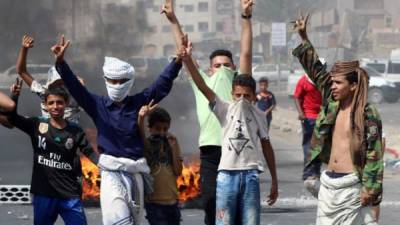 Jóvenes yemenitas vislumbran la V como señal de victoria cerca de la quema de neumáticos mientras los manifestantes protestan contra la inflación y el aumento de los costos de vida en la segunda ciudad de Adén.