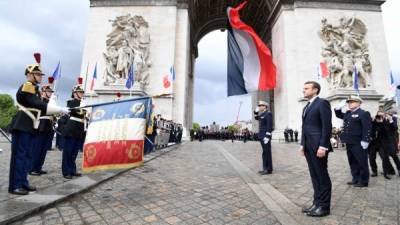 TOPSHOT - French President Emmanuel Macron (C) stands after laying a wreath on the unknown Soldier's tomb at the Arc of Triomphe monument after his formal inauguration ceremony as French President on May 14, 2017 in Paris. / AFP PHOTO / POOL AND AFP PHOTO / ALAIN JOCARD