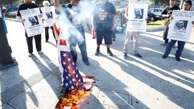 Manifestantes queman una bandera estadounidense durante una protesta por el asesinato de afroamericanos a manos de la policía. AFP.