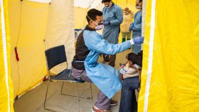 Personal médico le toma la temperatura a pacientes con sospechas de Covid-19. Foto: AFP