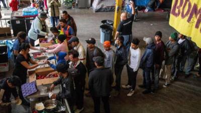 En la imagen, organismos en apoyo al migrante repartieron alimentos en una cena de Nochevieja en el albergue “contra viento y marea”, uno de los lugares donde han sido ubicados integrantes de la caravana de migrantes centroamericanos. (Tijuana, México). EFE