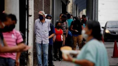 Decenas de personas hacen fila para recibir alimentos de manos de voluntarios que con la ayuda del restaurante Rayuela crearon un sistema de cocina y entrega de alimentos a personas afectadas económicamente por las medidas de restricción y movilidad tomadas por el Gobierno para combatir el coronavirus en el centro histórico de Ciudad de Guatemala. EFE/Esteban Biba