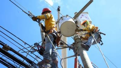 Dos empleados de la Empresa Energía Honduras reparando parte del tendido eléctrico. Archivo.