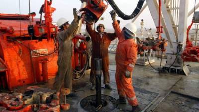 Trabajadores de Oil Company cambian tuberías en una perforadora.