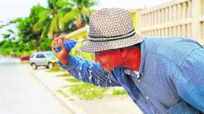 Un ciudadano echándose agua para refrescarse.