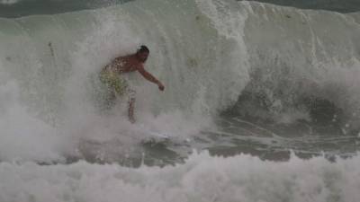 Un surfista desafía el peligro al practicar su deporte en Miami Beach.