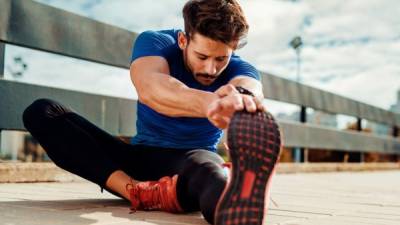 Young male jogger athlete training and doing workout outdoors in city