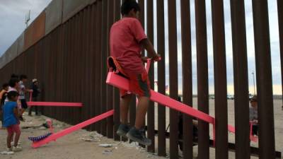 Niños mexicanos y estadounidenses juegan en un subibajas instalado en el muro que separa a Tijuana de San Diego./AFP.