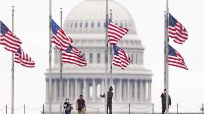 Funcionarios de Parques Nacionales ondean las banderas a media asta, este 12 de mayo de 2022 en Washington, para recordar a los fallecidos por covid-19, que superan el millón de personas en el país.