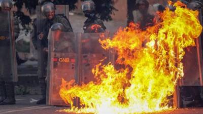 Miembros de la Guardia Nacional Bolivariana (GNB) se protegen del fuego en medio de unos enfrentamientos con manifestantes durante una de las protestas en el marco de la huelga general de dos días convocada por la oposición en Caracas (Venezuela). EFE