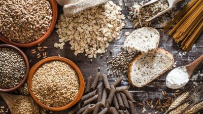 Top view of wholegrain and cereal composition shot on rustic wooden table. This type of food is rich of fiber and is ideal for dieting. The composition includes wholegrain sliced bread, various kinds of wholegrain pasta, wholegrain crackers, grissini, oat flakes, brown rice, spelt and flax seeds. Predominant color is brown. DSRL studio photo taken with Canon EOS 5D Mk II and Canon EF 100mm f/2.8L Macro IS USM