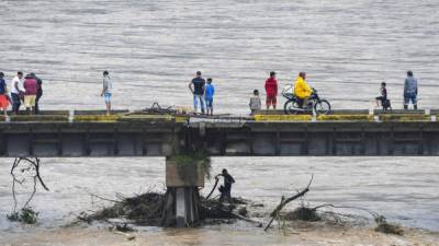 La gente observa la inundación del río Humuya debido a las fuertes lluvias causadas por el huracán Eta, en Santa Rita, departamento de Yoro. AFP