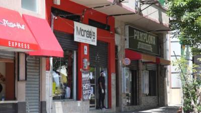 Un empleado espera afuera de una tienda en el centro de San Pedro Sula. Foto: Franklyn M.