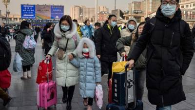 TOPSHOT - People wearing protective masks arrive at Beijing railway station to head home for the Lunar New Year on January 21, 2020. - China has confirmed human-to-human transmission in the outbreak of a new SARS-like virus as the number of cases soared and the World Health Organization said it would consider declaring an international public health emergency. (Photo by NICOLAS ASFOURI / AFP)
