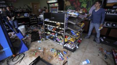Empleados de un negocio limpian el local que fue saqueado por manifestantes en la madrugada del viernes en Tegucigalpa, Honduras.