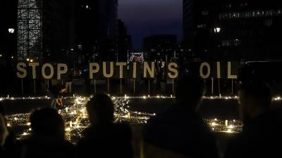 Activistas ucranianos protestan en Bruselas con un letrero que pide “detener el petróleo de Putin”.