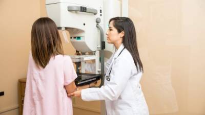 Pretty female doctor setting a patient in the correct position to get a mammogram in a clinic