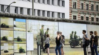Varias personas observan la instalación 'Más Allá del Muro' en Berlín (Alemania). EFE