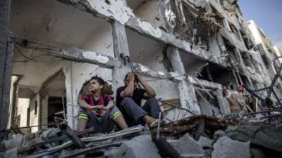 Dos niños palestinos lamentan la destrucción de su hogar en Gaza.