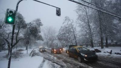 Vehículos transitan en una calle cubierta de nieve hoy, sábado 15 de julio de 2017, en Santiago (Chile). EFE