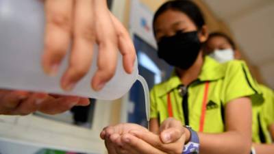 Estudiantes de Camboya desinfectan sus manos con una solución de alcohol antes de ingresar a la clase en una escuela en Phnom Penh.El Ministerio de Salud de Camboya informó el primer caso del país del coronavirus mortal el 27 de enero. Foto: AFP