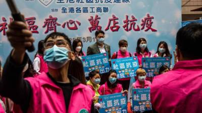 Militantes pro-Pekín regalan mascarillas en un mercado de Hong kong