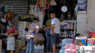 Unas personas son vistas mientras buscan productos básicos en un pequeño mercado, este jueves en Tegucigalpa (Honduras).
