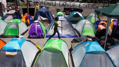 Una mujer camina en una calle donde permanece un grupo de manifestantes opositores al Gobierno del presidente venezolano, Nicolas Maduro, quienes protestan acampando frente a las oficinas de la Organización de las Naciones Unidas (ONU) en Caracas (Venezuela). EFE