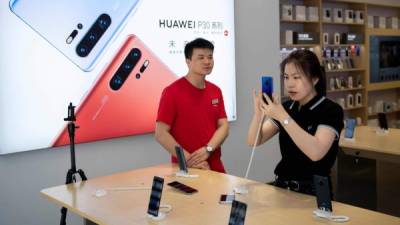 A store staff (L) attends a customer checking a Huawei smartphone in a store in Beijing on May 21, 2019. - Huawei founder Ren Zhengfei on May 21 shrugged off US attempts to block his company's global ambitions, saying the United States underestimates the telecom giant's strength. (Photo by Nicolas ASFOURI / AFP)