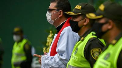 Sacerdote católico junto a varios oficiales policiales durante las ceremonias del Viernes Santo, obsevadas ayer en Cali.