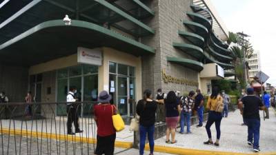 Clientes atienden medidas en las afueras de una agencia bancaria en San Pedro Sula. Foto: M. Cubas