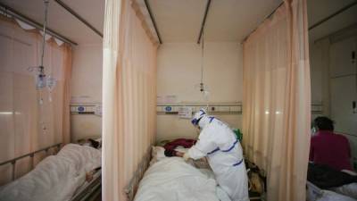 A medical staff member treats a patient infected by the COVID-19 coronavirus at Red Cross Hospital in Wuhan in China's central Hubei province on March 11, 2020. - China announced on March 11 that key companies will be allowed to resume work in coronavirus-hit Wuhan, in another sign authorities are confident the quarantined city is winning its battle against the epidemic. (Photo by STR / AFP) / China OUT