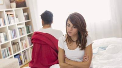 Sad couple after an argument in bed turned their back to each other sitting on the bed angry