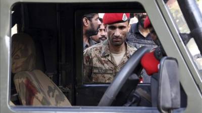 Un agente paquistaní mira en el interior del vehículo policial que fue objetivo de un ataque en Karachi (Paquistán). EFE/Archivo.