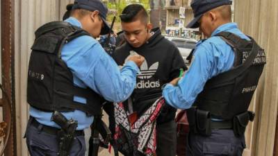 Policías revisan a un joven afuera de una escuela en Tegucigalpa. AFP