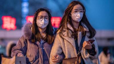 Two women wearing protective masks walk outside Beijing railway station in Beijing on January 22, 2020. - A new virus that has killed nine people, infected hundreds and reached the United States could mutate and spread, China warned on January 22, as authorities urged people to steer clear of the city at the heart of the outbreak. (Photo by NICOLAS ASFOURI / AFP)