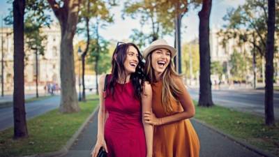 Happy girlfriends are walking and hugging in the city and make fun together