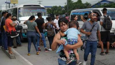 Una mujer lleva a su hijo en brazos después de que no encontrara un medio de transporte para desplazarse hacia su lugar de destino.