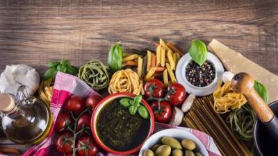 Italian and Mediterranean food ingredients on old wooden background.Spaghetti olives basil pesto tomato pasta garlic pepper olive oil and mortar.