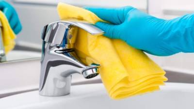 Woman doing chores in bathroom, cleaning tap
