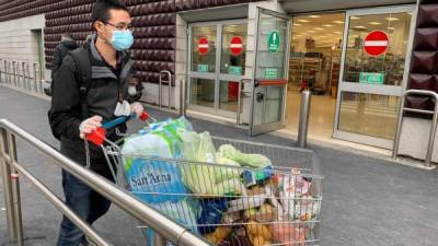 A man wearing a protective mask leaves a supermarket with trolleys full of shopping in Milan on March 8, 2020 as Italy quarantines more than 10 million people around the financial capital Milan and the tourist mecca Venice for nearly a month to halt the spread of the novel coronavirus, COVID-19. - The World Health Organization on March 8, 2020 saluted Italy's 'genuine sacrifices' after the government put a quarter of the population under lockdown to try to halt the spread of the novel coronavirus. (Photo by Miguel MEDINA / AFP)