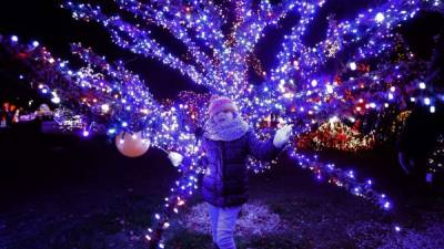 Una joven posa junto un árbol iluminado en Grabovnica. Adornan el lugar con más de dos millones de luces.