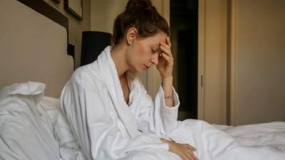 Young sad woman sitting in the bed, depression, anxiety, relationship difficulties, migraine or morning sickness concept