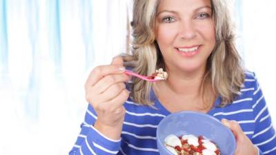 Happy matured woman eating healthy food