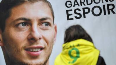 An FC Nantes supporter stands beside a portrait of Argentinian striker Emiliano Sala prior to a team training session at the training centre La Joneliere in La Chapelle-sur-Erdre, western France, on January 24, 2019, three days after the plane carrying Sala vanished over the English Channel. - Police on January 24 ended their search for new Premier League player Emiliano Sala, saying the chances of finding the Argentine alive three days after his plane went missing over the Channel were 'extremely remote'. Sala, 28, was on his way from Nantes in western France to the Welsh capital to train with his new teammates for the first time after completing a £15 million ($19 million) move to Cardiff City from French side Nantes on January 19. (Photo by LOIC VENANCE / AFP)
