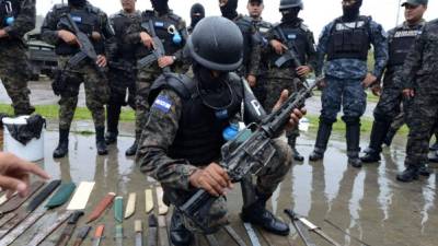 Un miembro de la Policía Militar muestra un rifle AR-15 decomisado a los reclusos en el penal de Marco Aurelio Soto en Támara. AFP