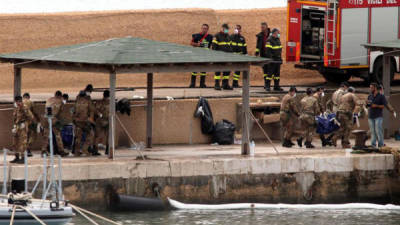 Varios militares italianos trasladan los cadáveres de víctimas del naufragio del barco de inmigrantes que tuvo lugar frente a la isla de Lampedusa, en el puerto de Lampedusa (Italia),