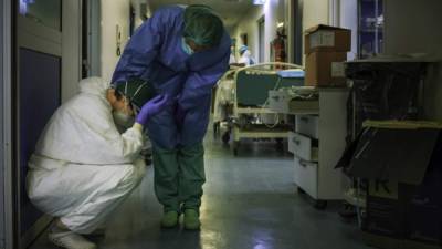 Una enfermera con máscara protectora y equipo conforta a otro mientras cambian de turno en el hospital de Cremona, al sureste de Milán.