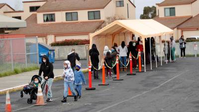 Padres con sus hijos esperan en la fila para hacerse la prueba de COVID-19 en la Escuela Primaria Ohlone en Hercules, California, EEUU.